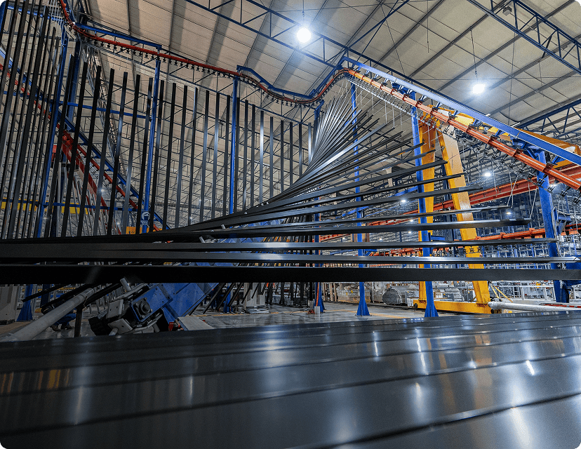 Metal bars move on a conveyor, through a factory.